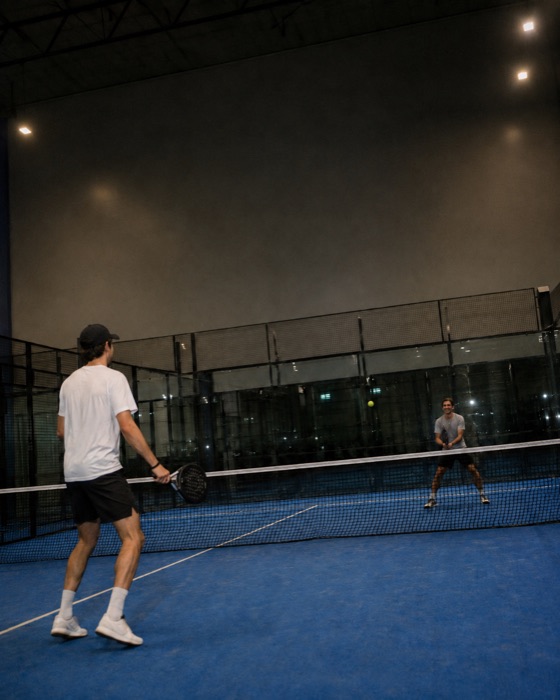 Two friends playing padel at night